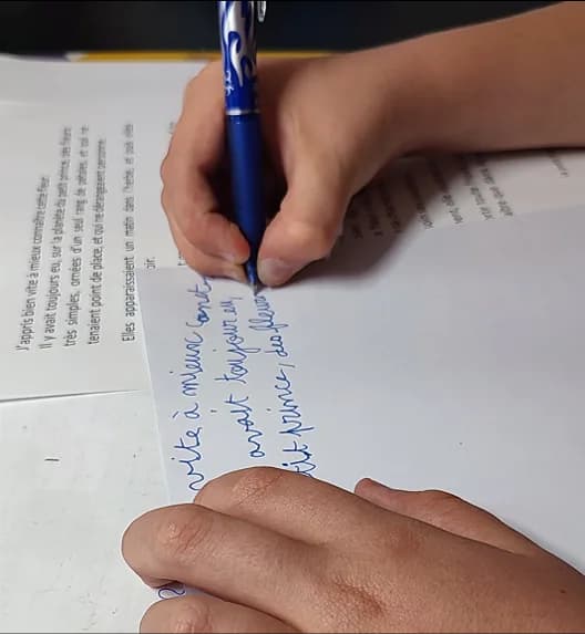 Un enfant recopie un texte au stylo lors du bilan